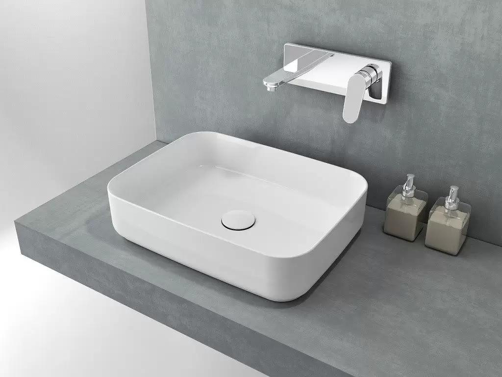 Раковина накладная Isvea Infinity 50 см, белый матовый — на серой бетонной стене с флаконами